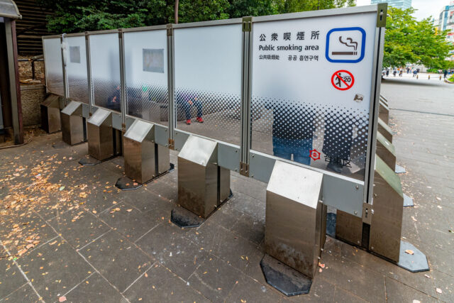 Designated outdoor public smoking area in  Ueno park, Tokyo with enclosed partitions and signage.