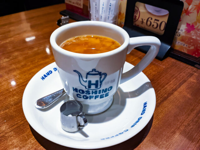 Cup of coffee at Hoshino Coffee, a modern take on Japan’s traditional kissaten café, served with spoon and creamer on a white saucer