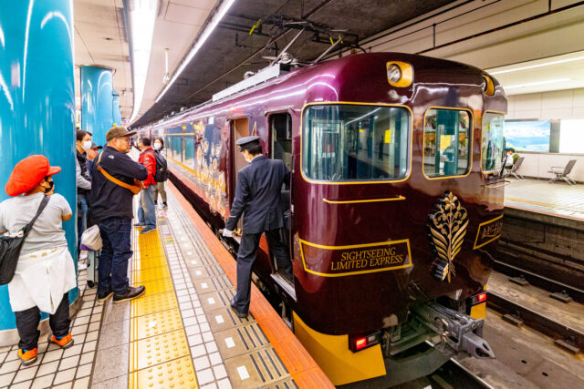 Purple Kintetsu Aoniyoshi Sightseeing Limited Express train at the platform in Osaka Namba with passengers boarding in Japan