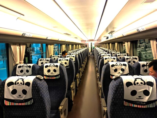 Interior of Panda Kuroshio train showing panda-decorated seat headrests and neatly arranged seating.