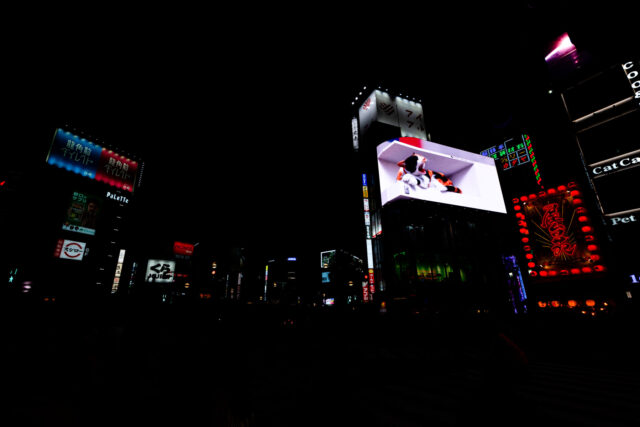 Night view of Shinjuku Station East Exit with the famous 3D giant calico cat billboard, neon lights, and Kabukicho signs in Tokyo Japan