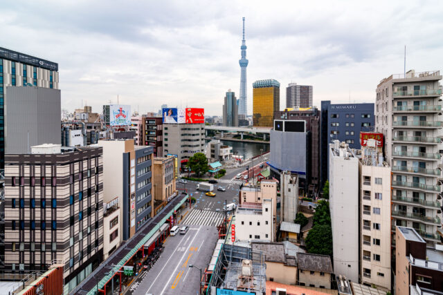 Tokyo Skytree and Asahi Beer Hall golden flame seen from Asakusa Tourist Information Center with view over Sumida River.