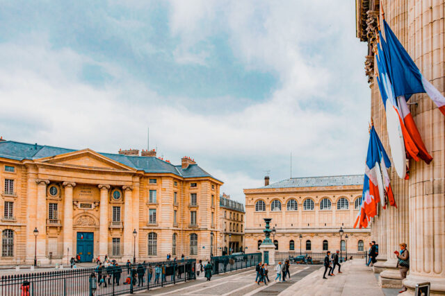 Panthéon steps with French flags overlooking Place du Panthéon and the 5th arrondissement town hall in Paris.