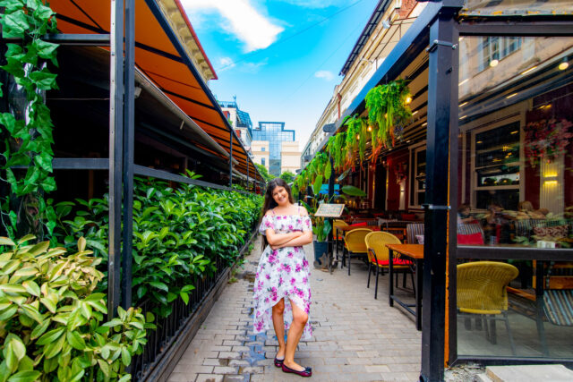 Shardeni Street in Tbilisi, Georgia, with vibrant cafes, outdoor seating, and a young woman posing in a floral high-low dress on the pedestrian walkway.